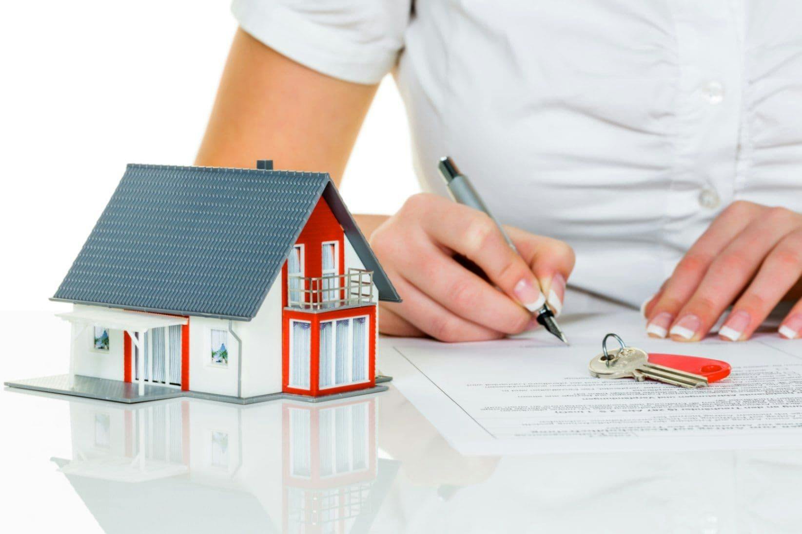 Grundlagen zur Immobilienfinanzierung werden durchgearbeitet. Ein Haus steht als Modell auf dem Tisch. Eine Person macht sich Notizen.